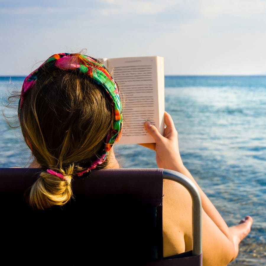 teen girl reading on the beach